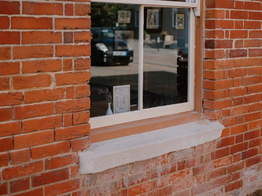 Red brick wall with a window and stone sill