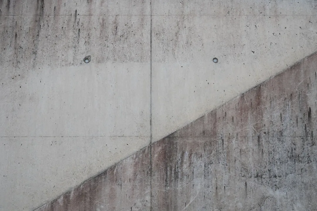 Rough concrete wall with diagonal stripe pattern and vertical lines.