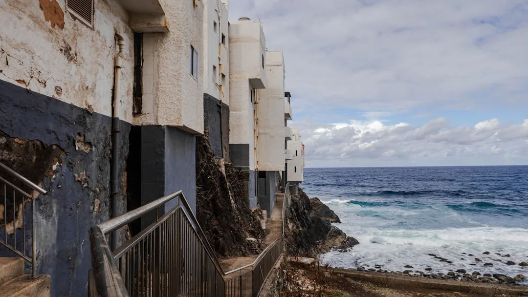 a building next to the ocean with a stairway going up to it